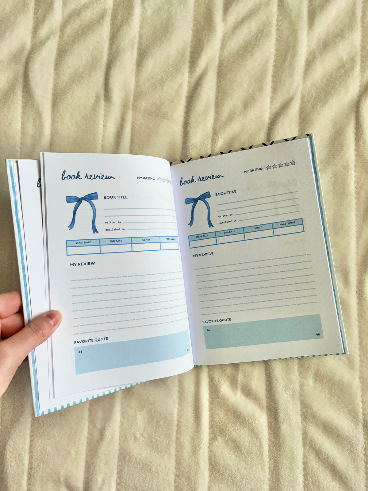 Open blue striped journal showing lined review pages with title and rating boxes