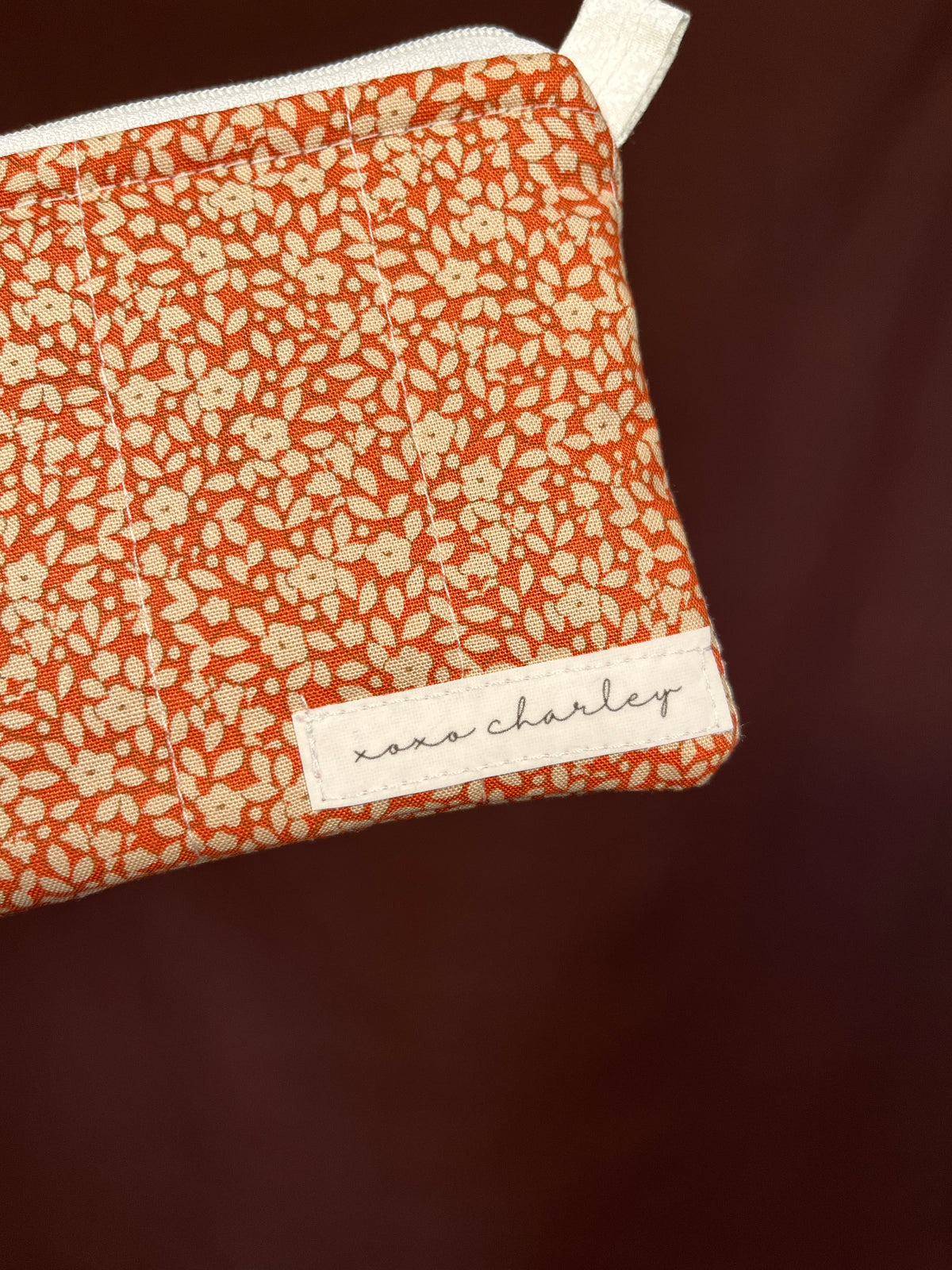 Orange floral keychain pouch wallet corner view with stitched brand label patch