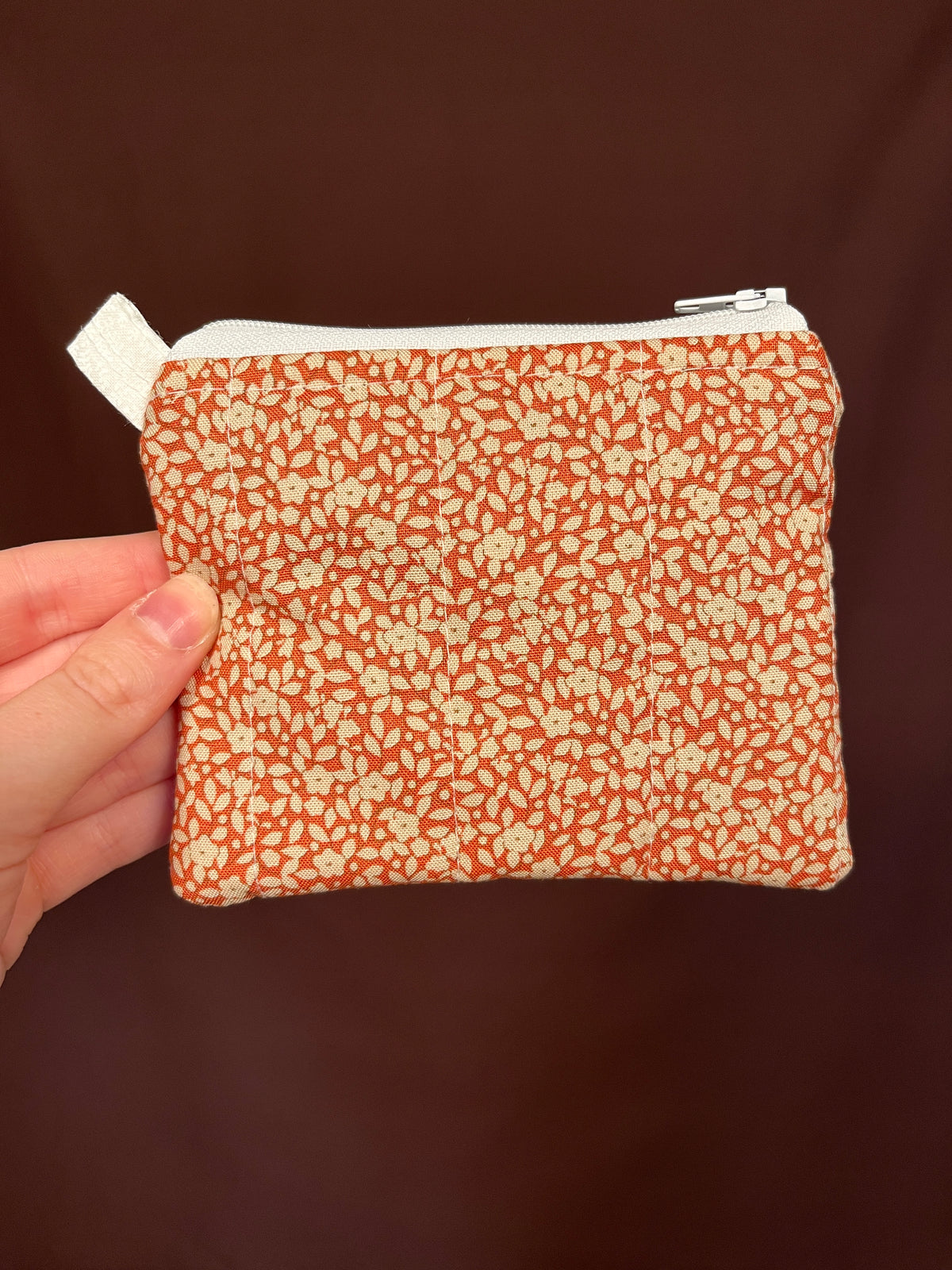 Orange floral keychain pouch wallet held in hand with metal zipper pull