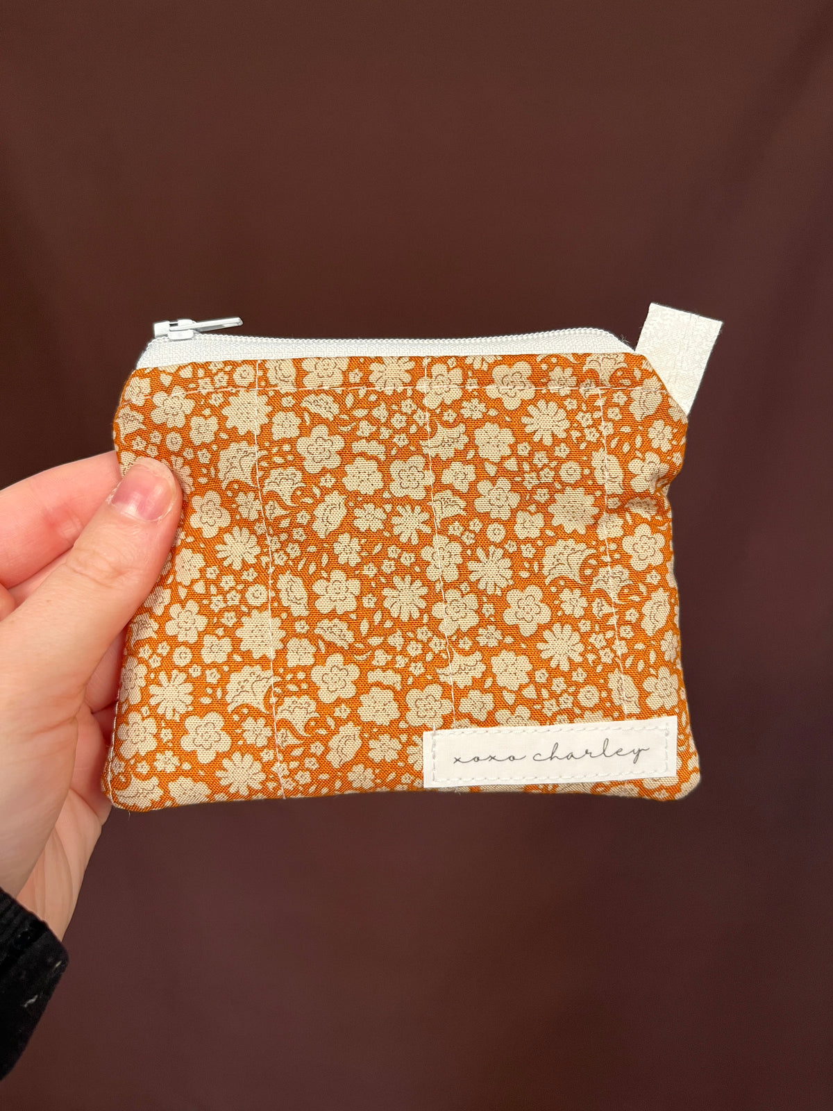 Orange floral keychain wallet with white zipper and fabric strap tab
