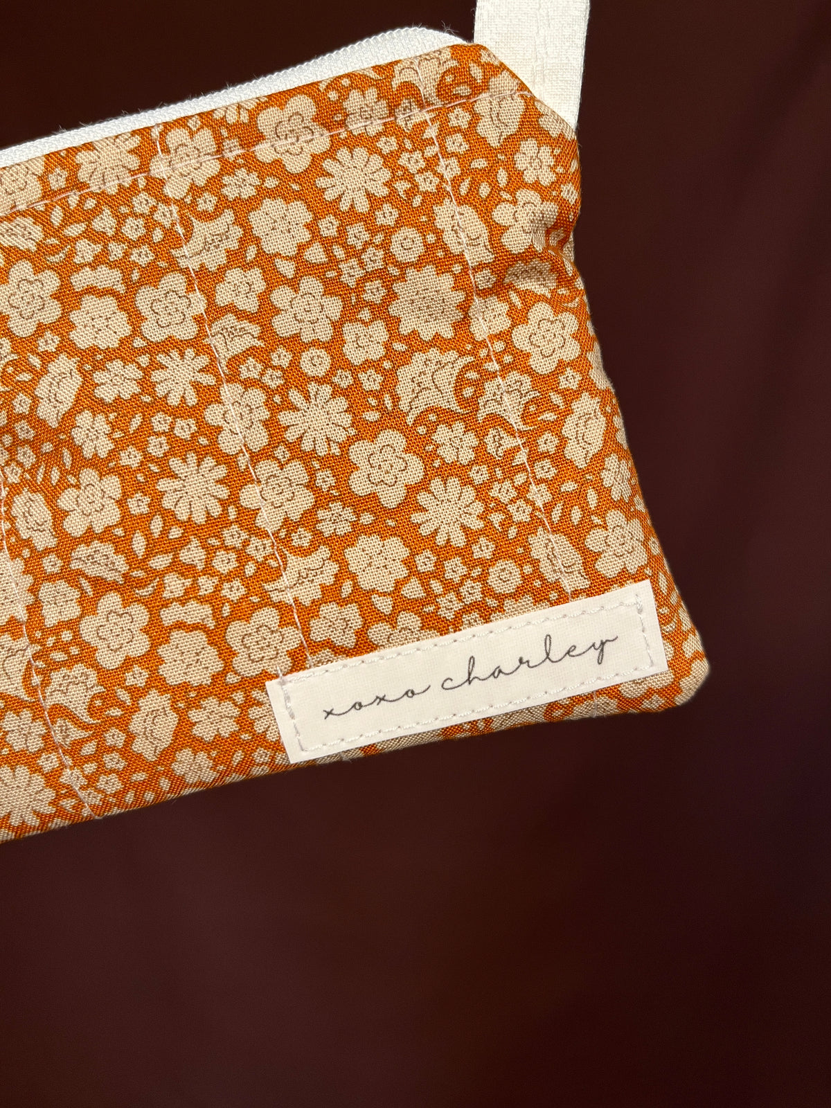 Orange floral keychain wallet front with white brand label