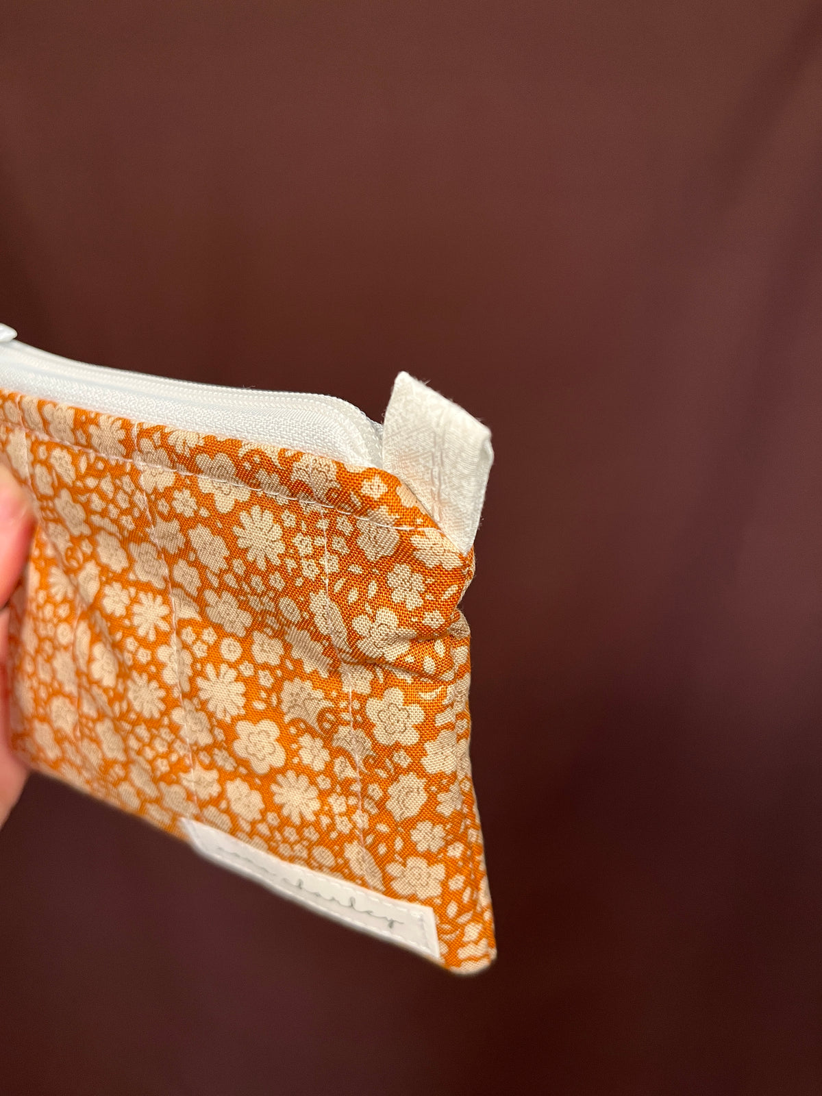 Orange floral keychain wallet with zippered edge and white lining