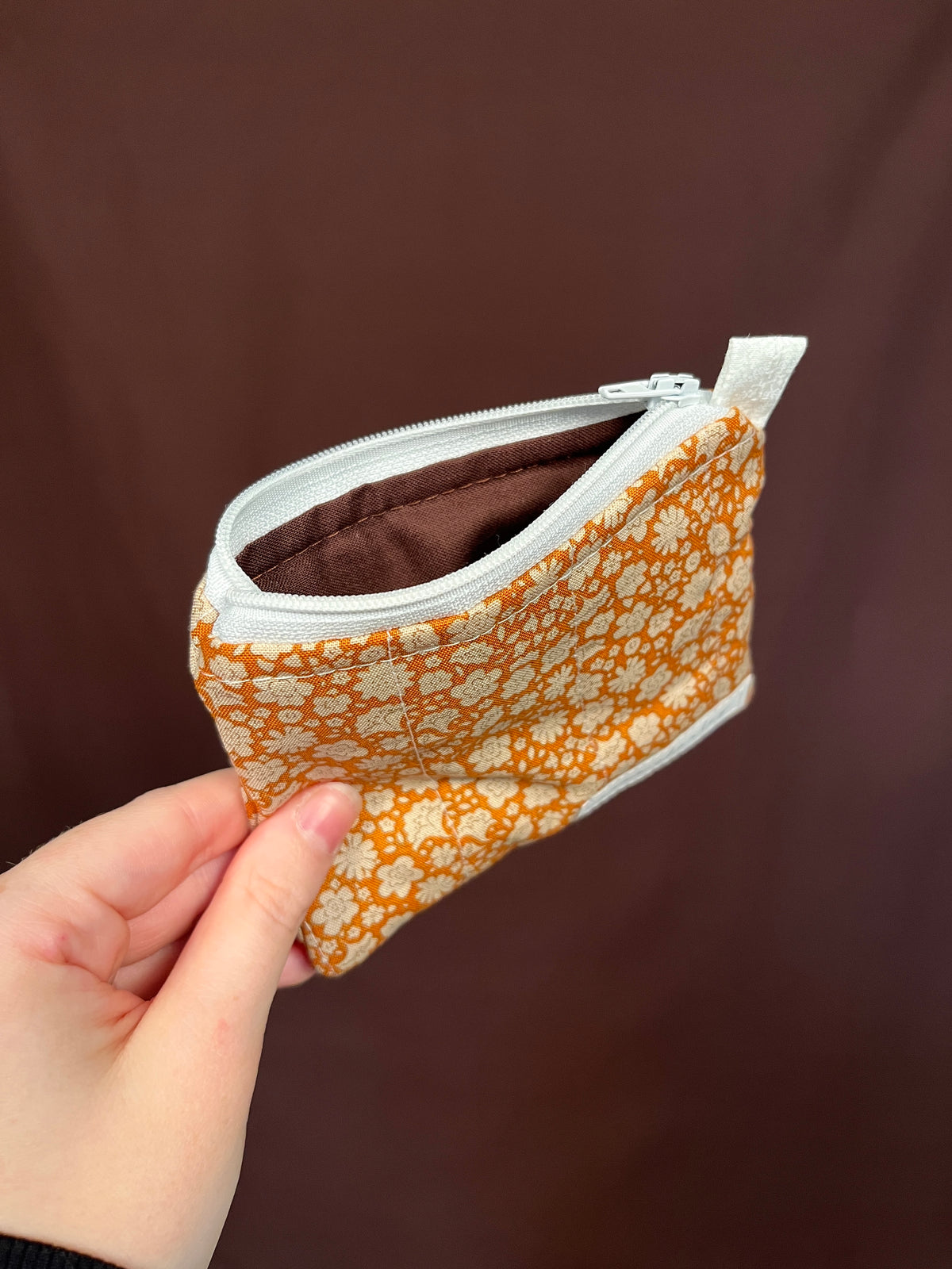 Orange floral keychain wallet with zipper open and brown card slot lining