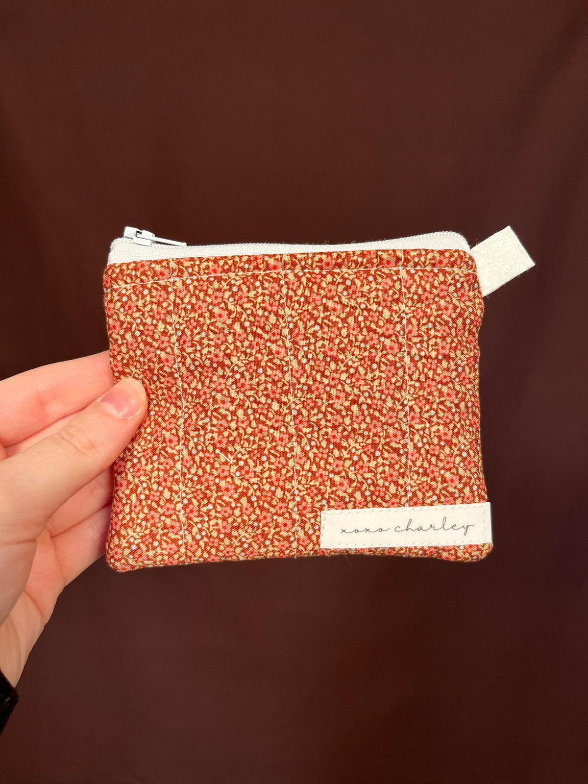 Orange speckled keychain wallet with zipper and white fabric tab label
