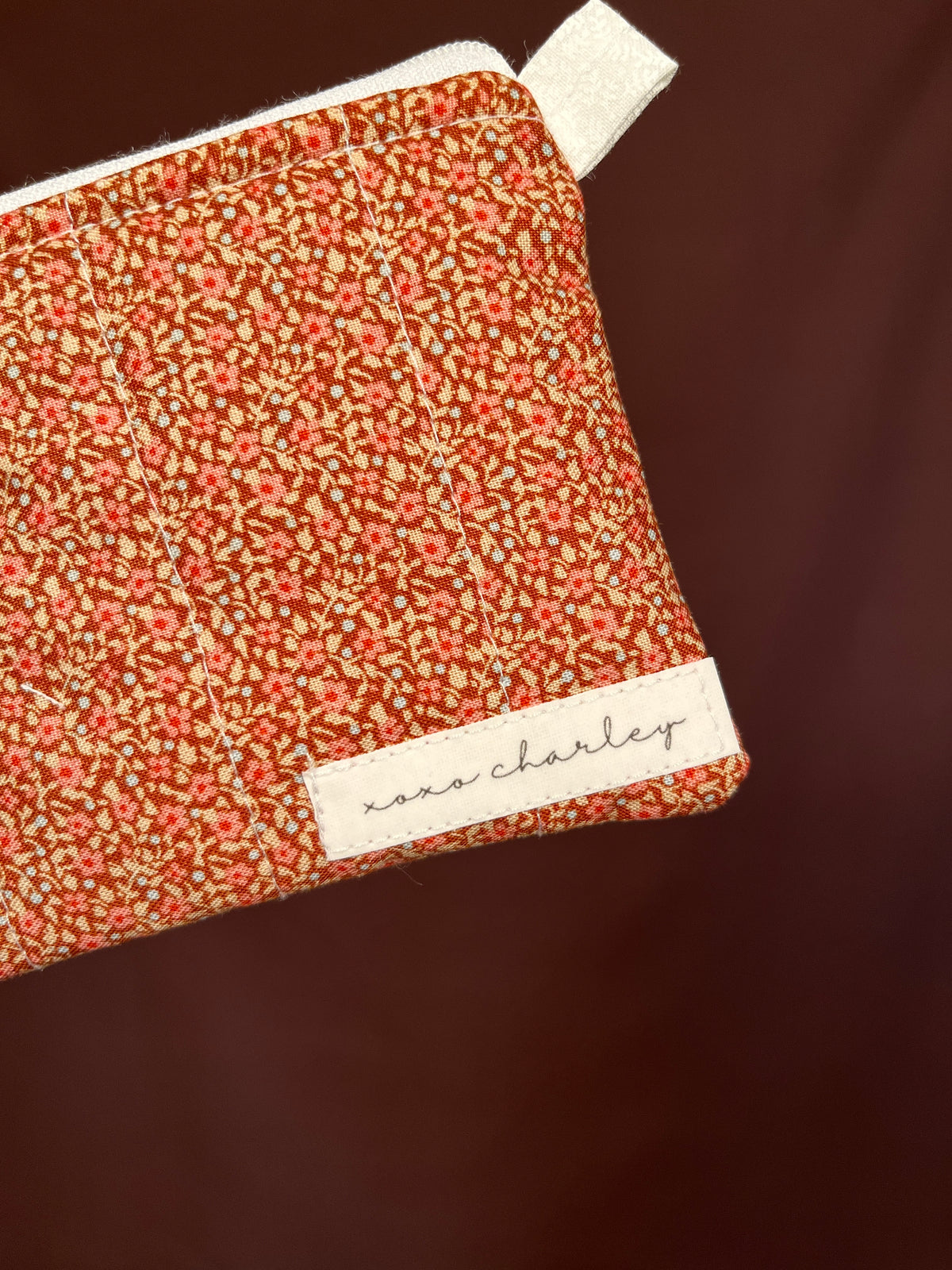 Orange speckled keychain wallet corner view with white label trim and zipper pull