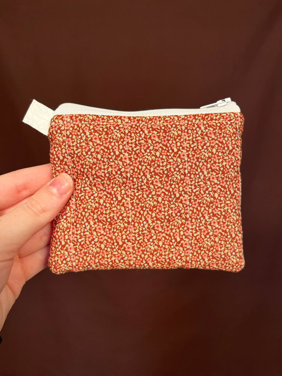 Orange speckled keychain wallet front view with zipper and hanging fabric loop