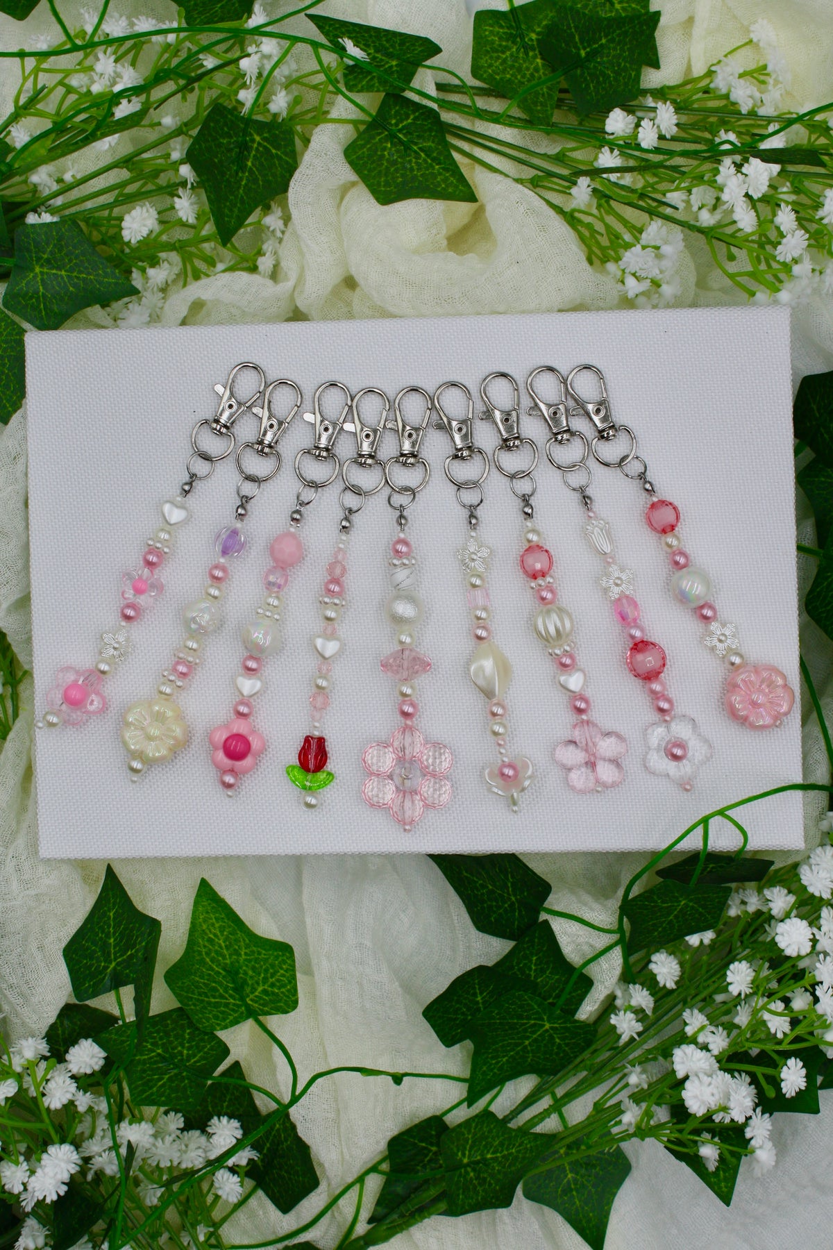 Set of beaded keychains with pink, white, and pastel flower charms on hooks