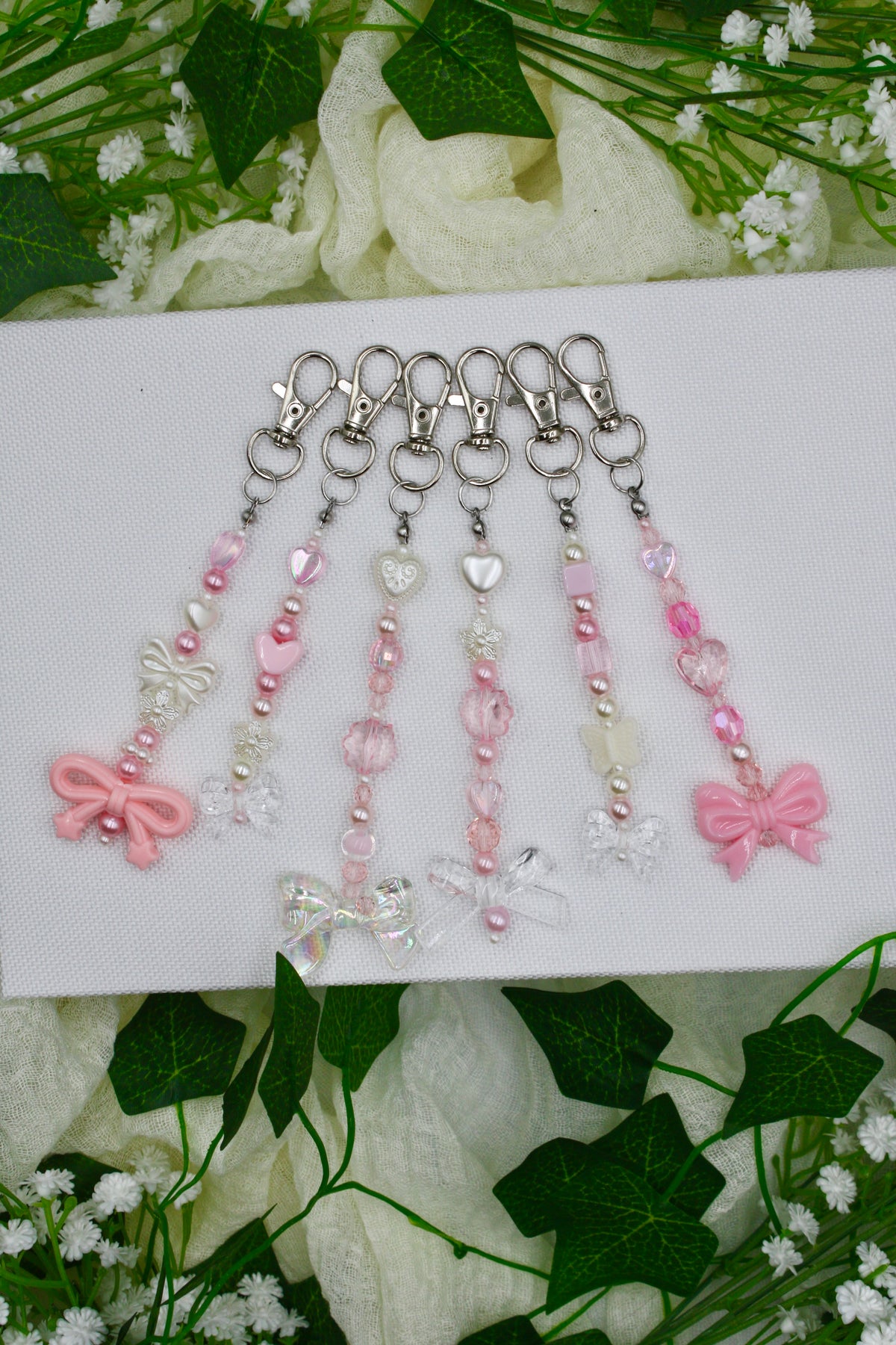Set of beaded keychains with pink hearts, bows, and small charms on silver key rings