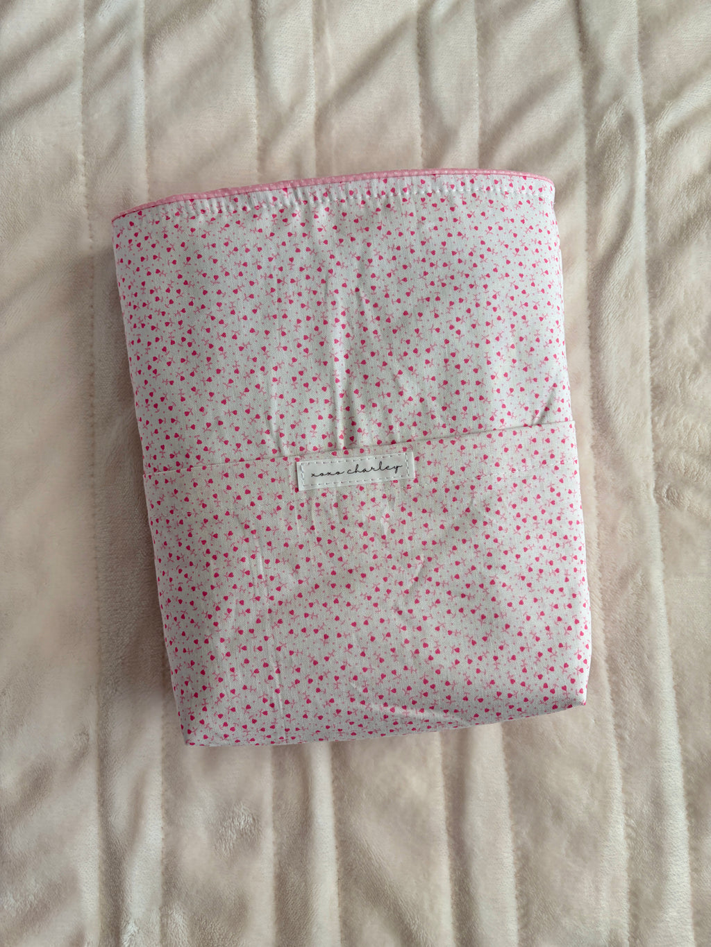 Pink heart-print fabric Bible sleeve with small central label, folded front.