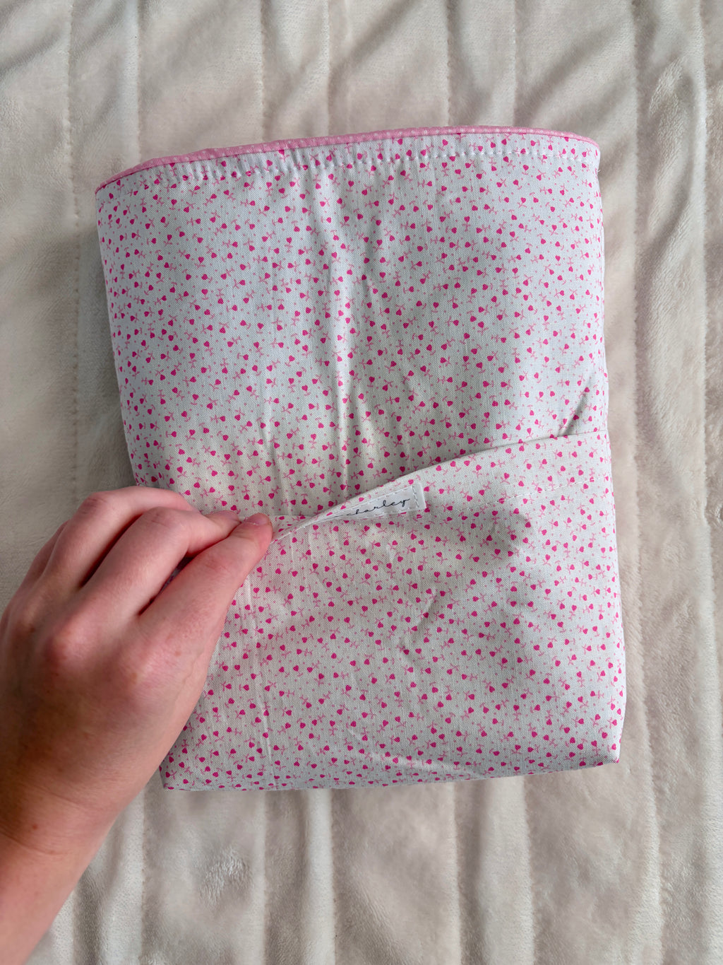 Pink heart-print Bible sleeve opened flat, showing pocket lining and seams.