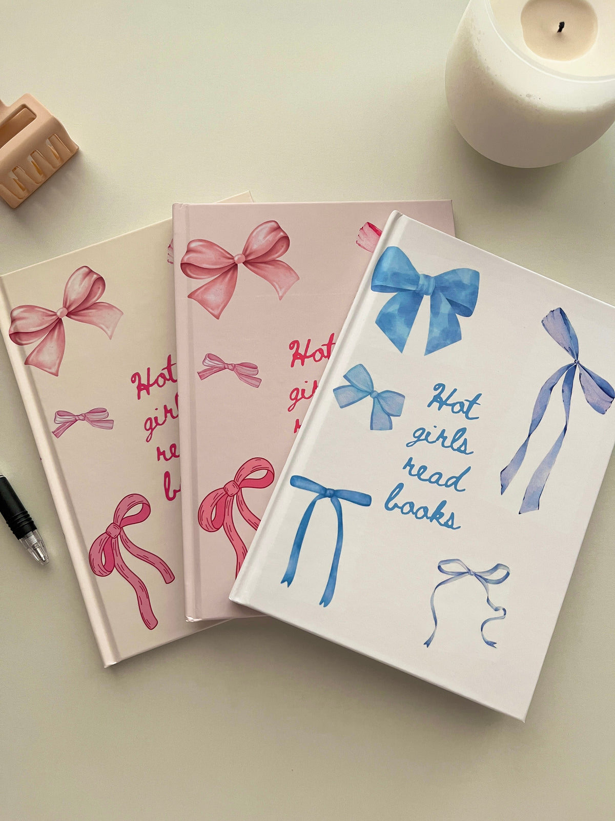 Set of reading journals with pink bow and blue bow cover designs on a desk.