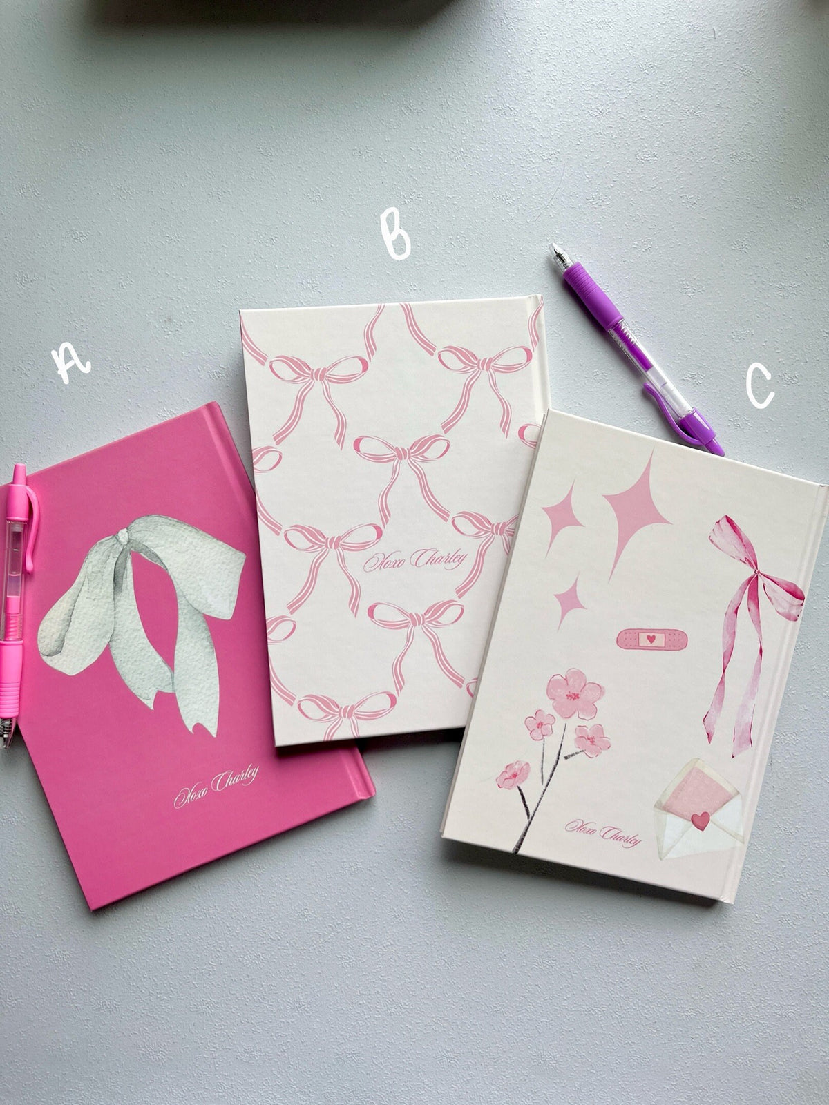 Mental health journals with pink and white covers, bow and flower designs, with pen