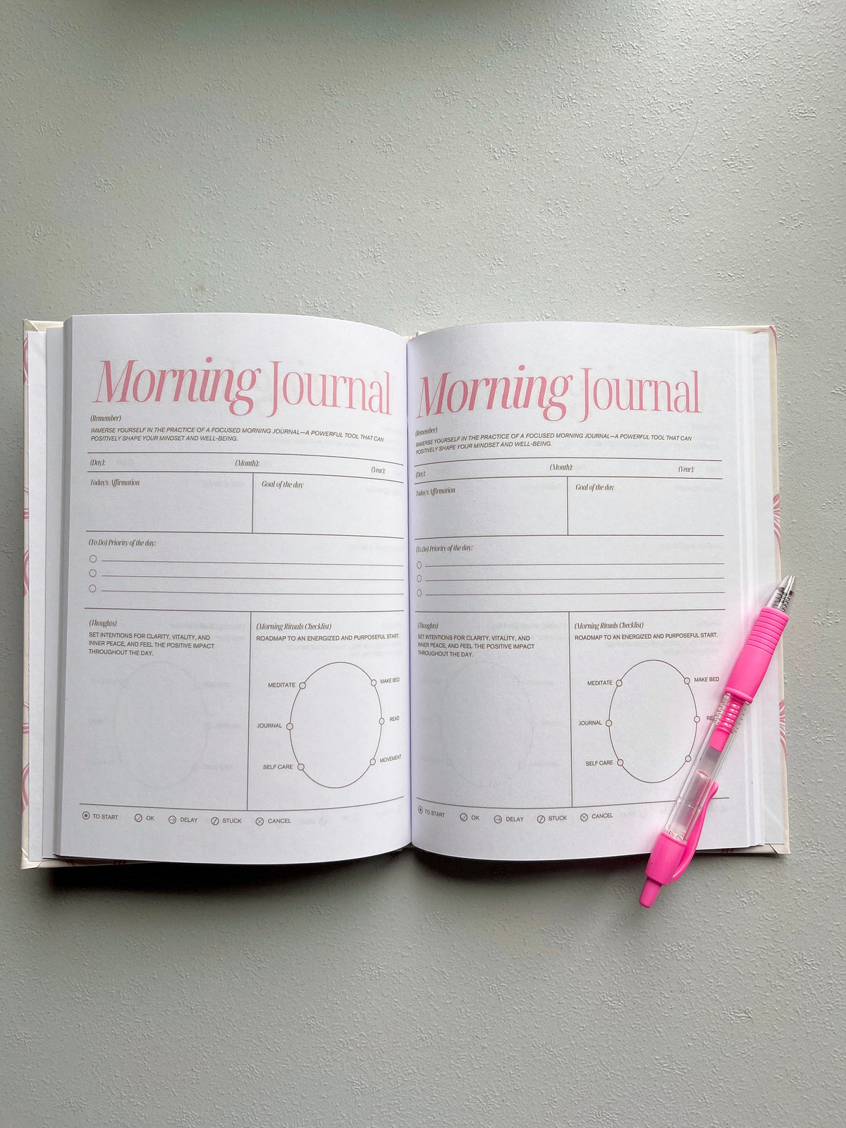 Open morning journal with printed prompts and checkboxes, plus pink pen
